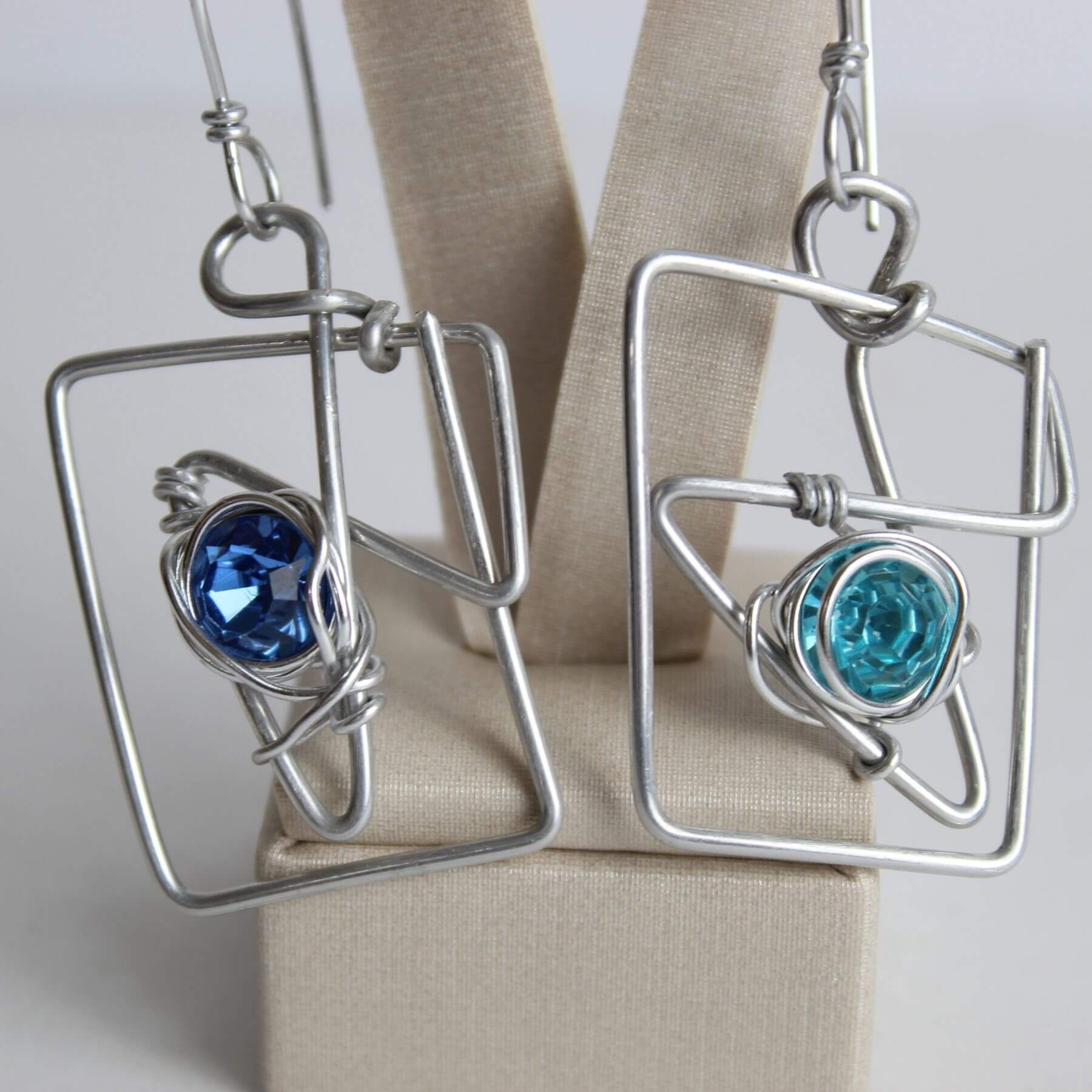 Detalhe dos brincos com pedras azuis em moldura de alumínio