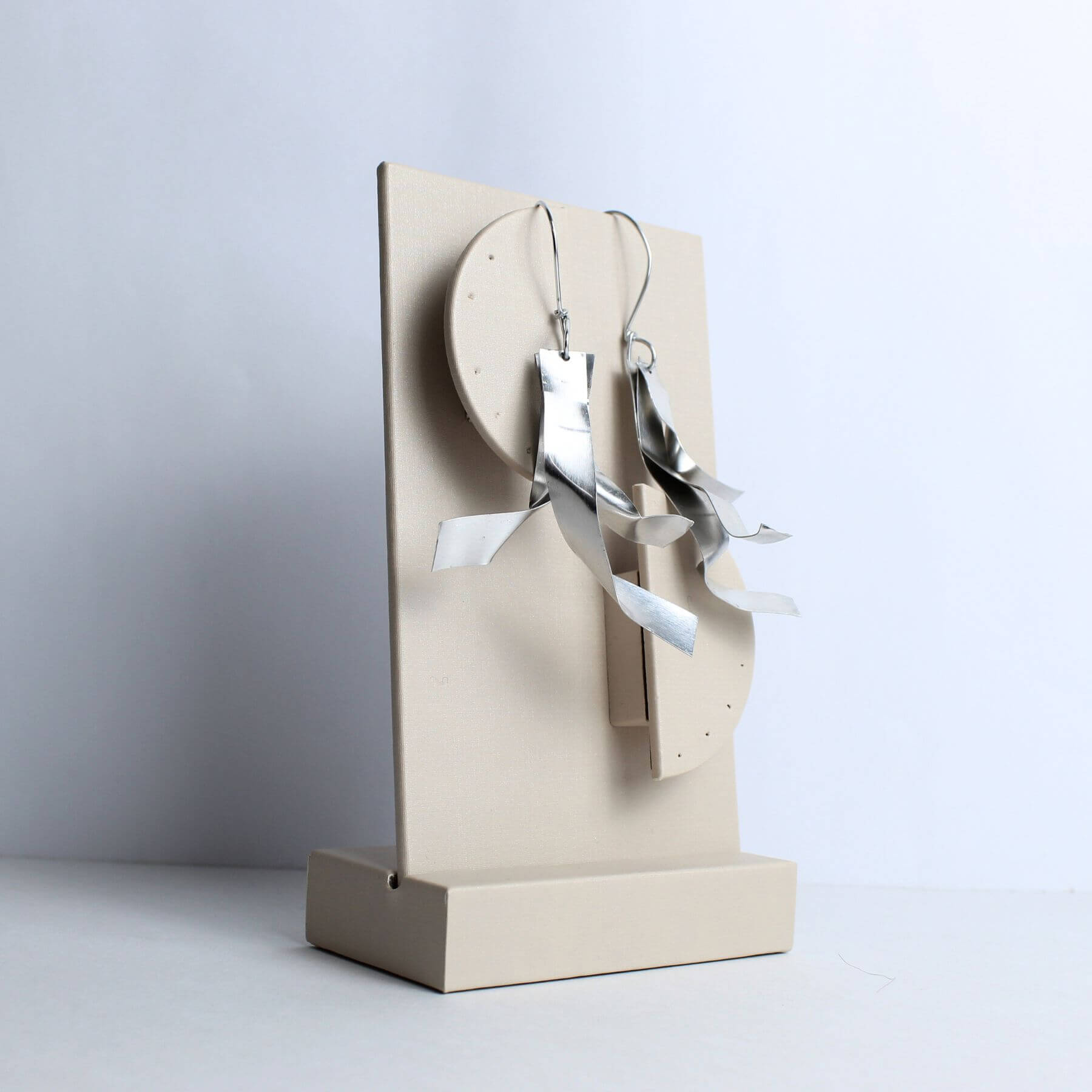 Brinco artesanal espiral feito à mão em alumínio com curvas torcidas e acabamento escovado