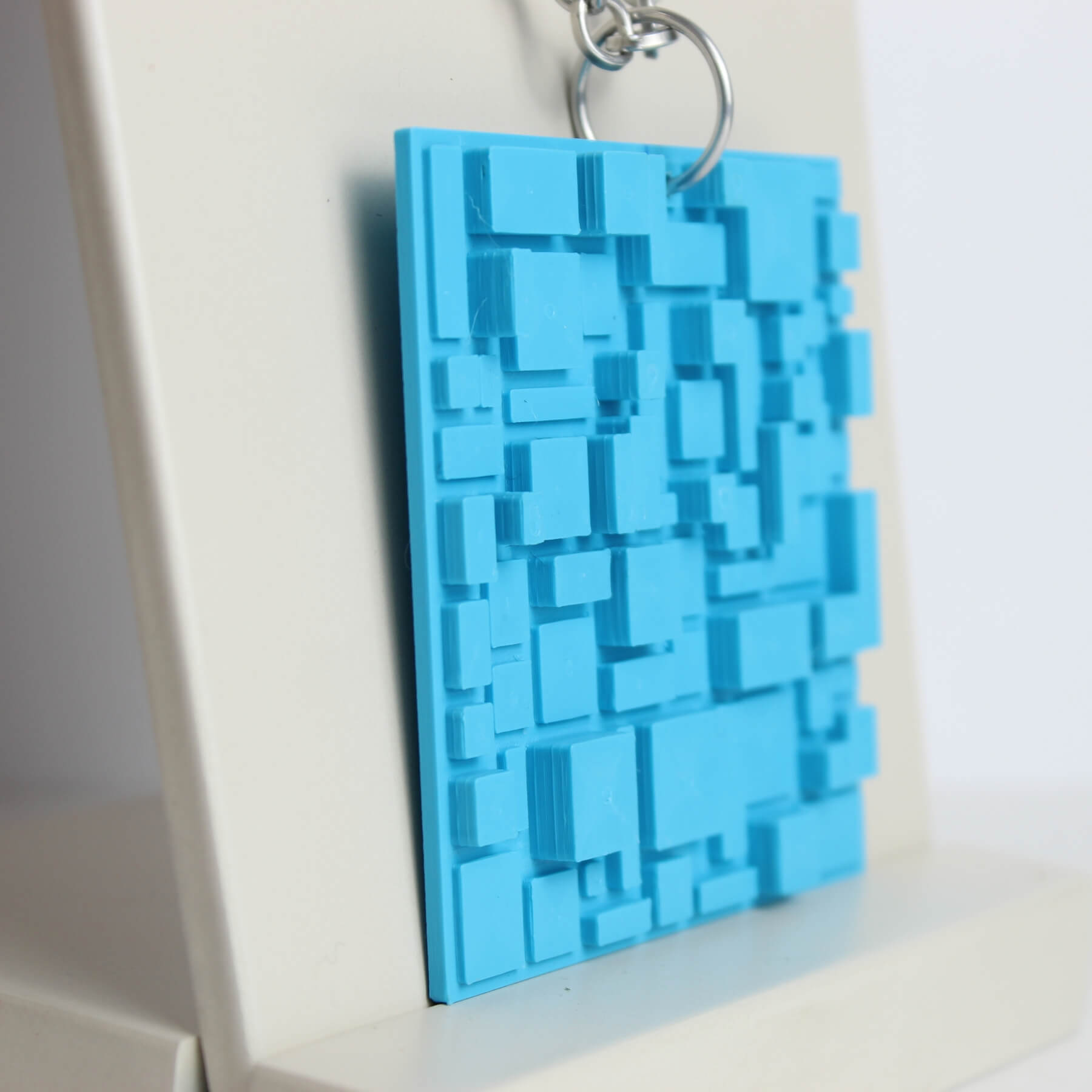 Pingente quadrado azul com textura tridimensional em PLA visto de perto