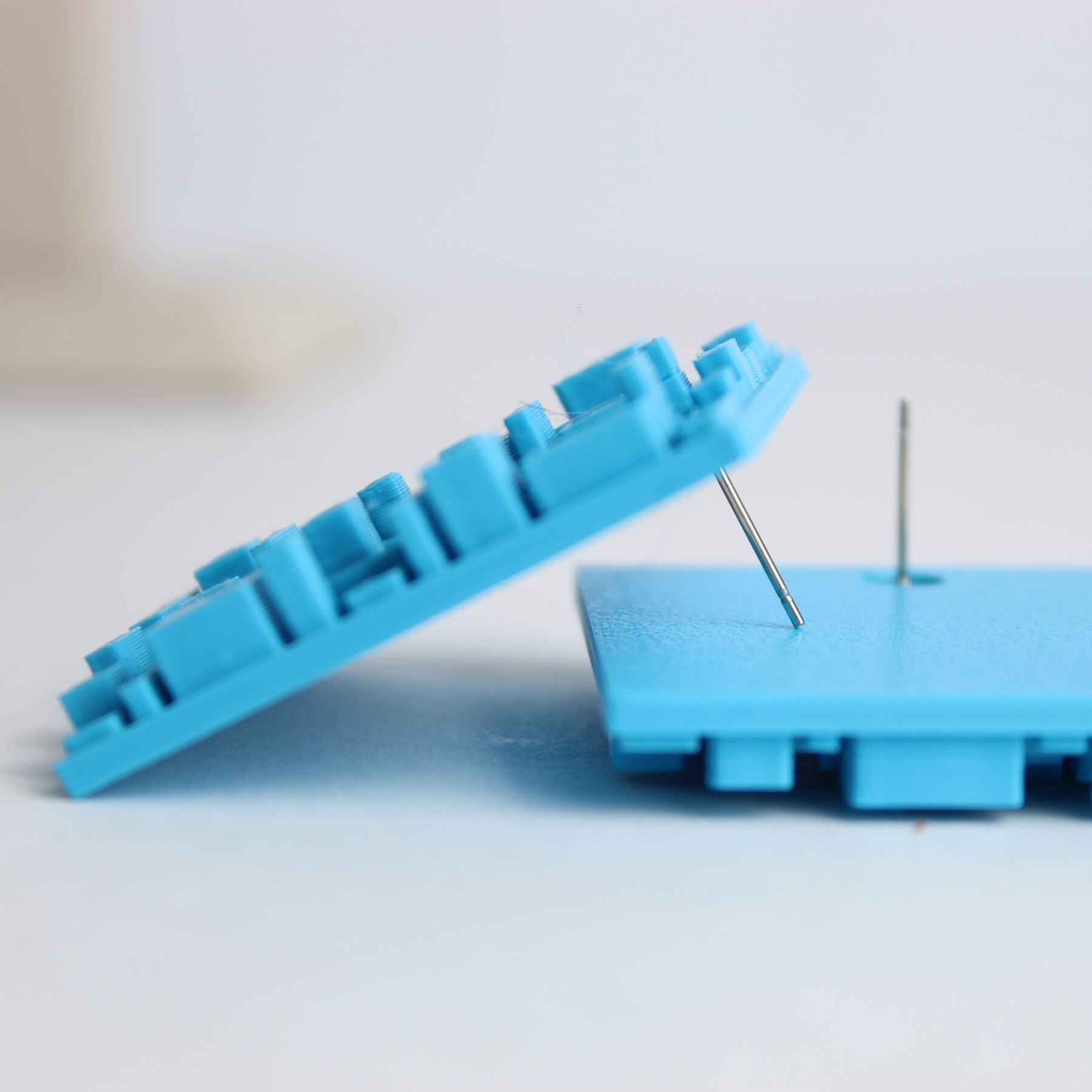 Vista lateral do brinco azul mostrando o pino de alumínio e tarraxa de silicone