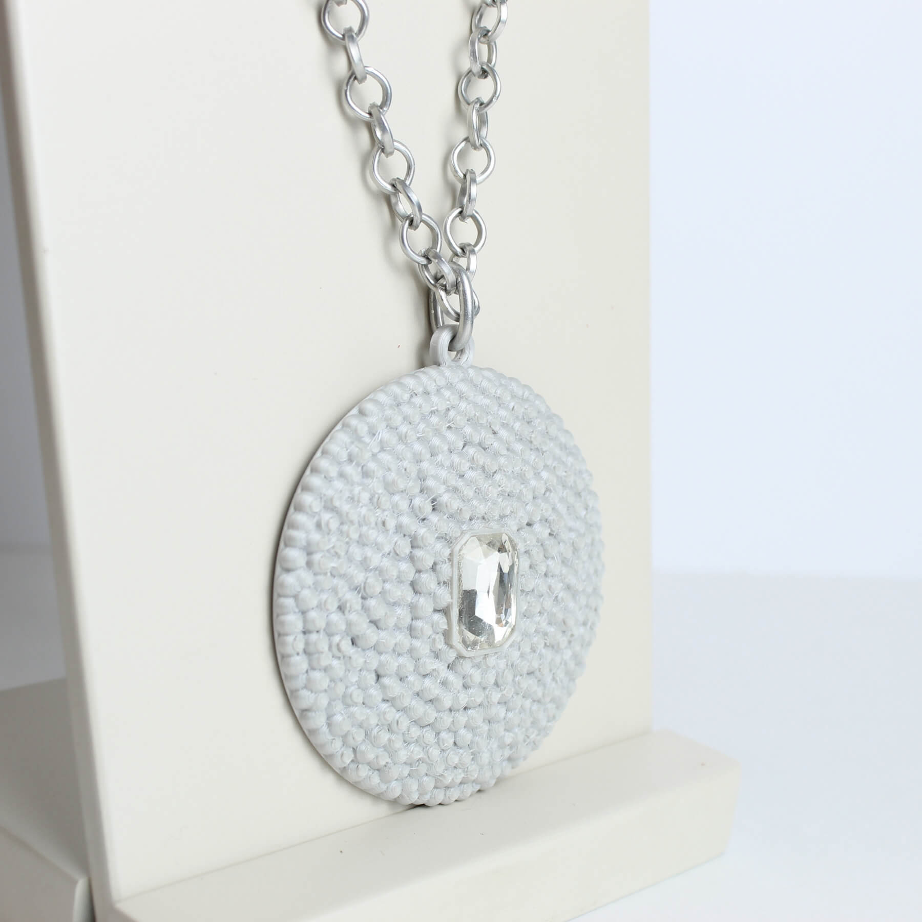 Close do pingente em PLA cinza com textura esférica e pedra artificial transparente ao centro