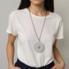 Mulher com camiseta branca vestindo colar longo com pingente em PLA texturizado e pedra transparente