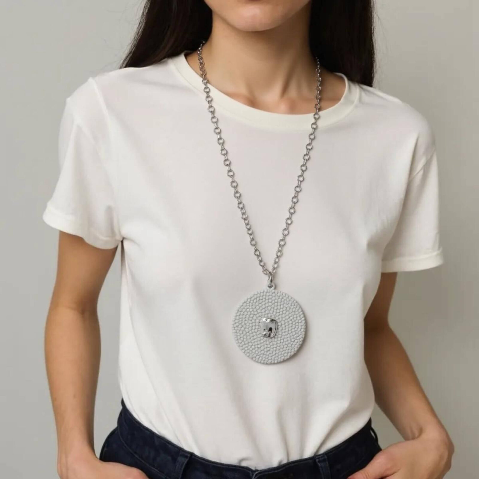 Mulher com camiseta branca vestindo colar longo com pingente em PLA texturizado e pedra transparente