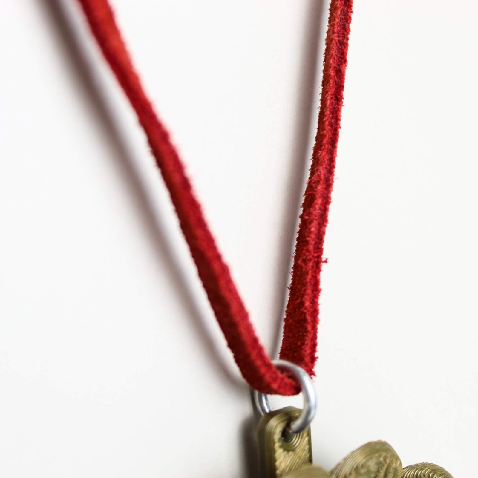 Close do cordão em couro vermelho mostrando textura aveludada