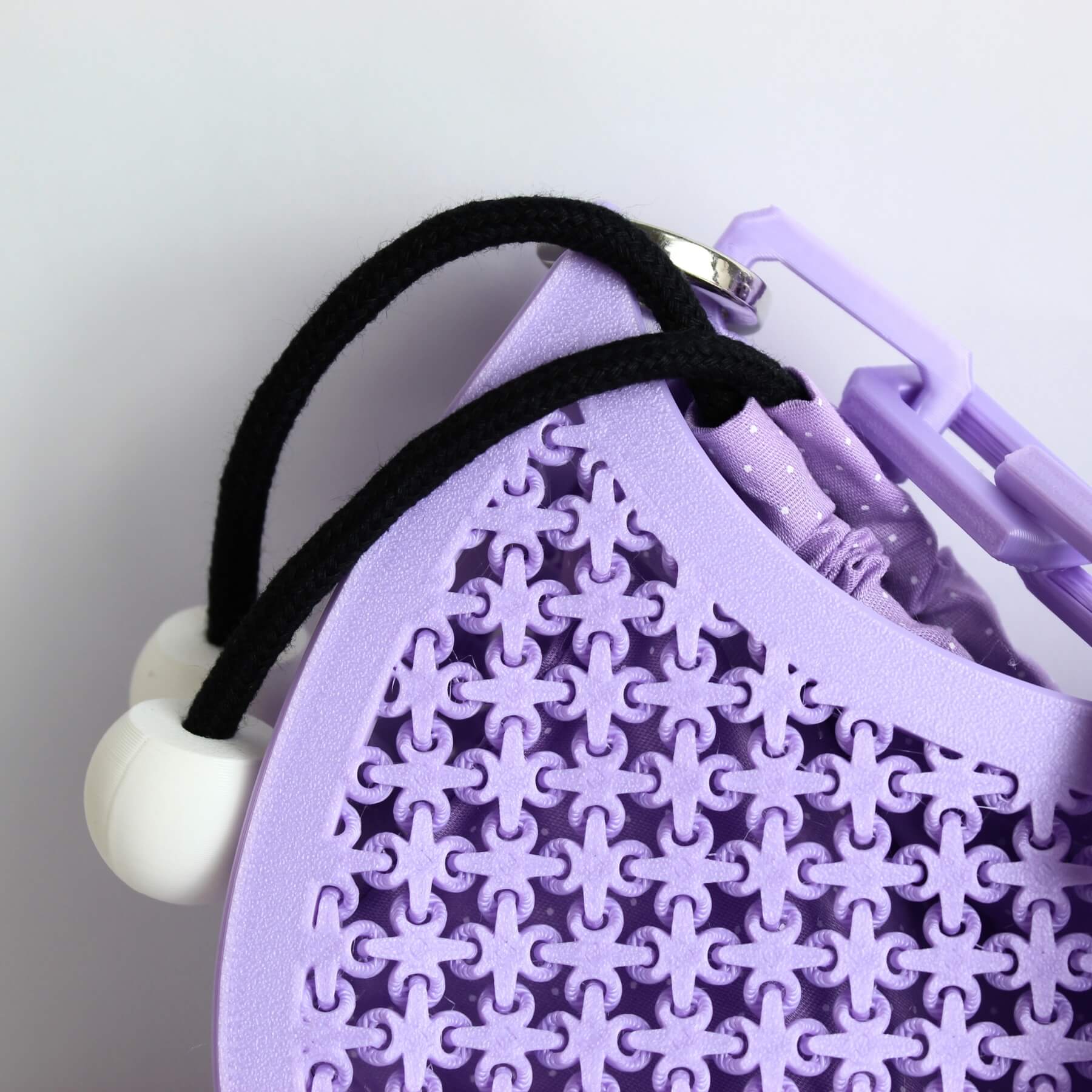 Parte superior da bolsa mostrando o cordão preto com esferas brancas e o acabamento do PLA