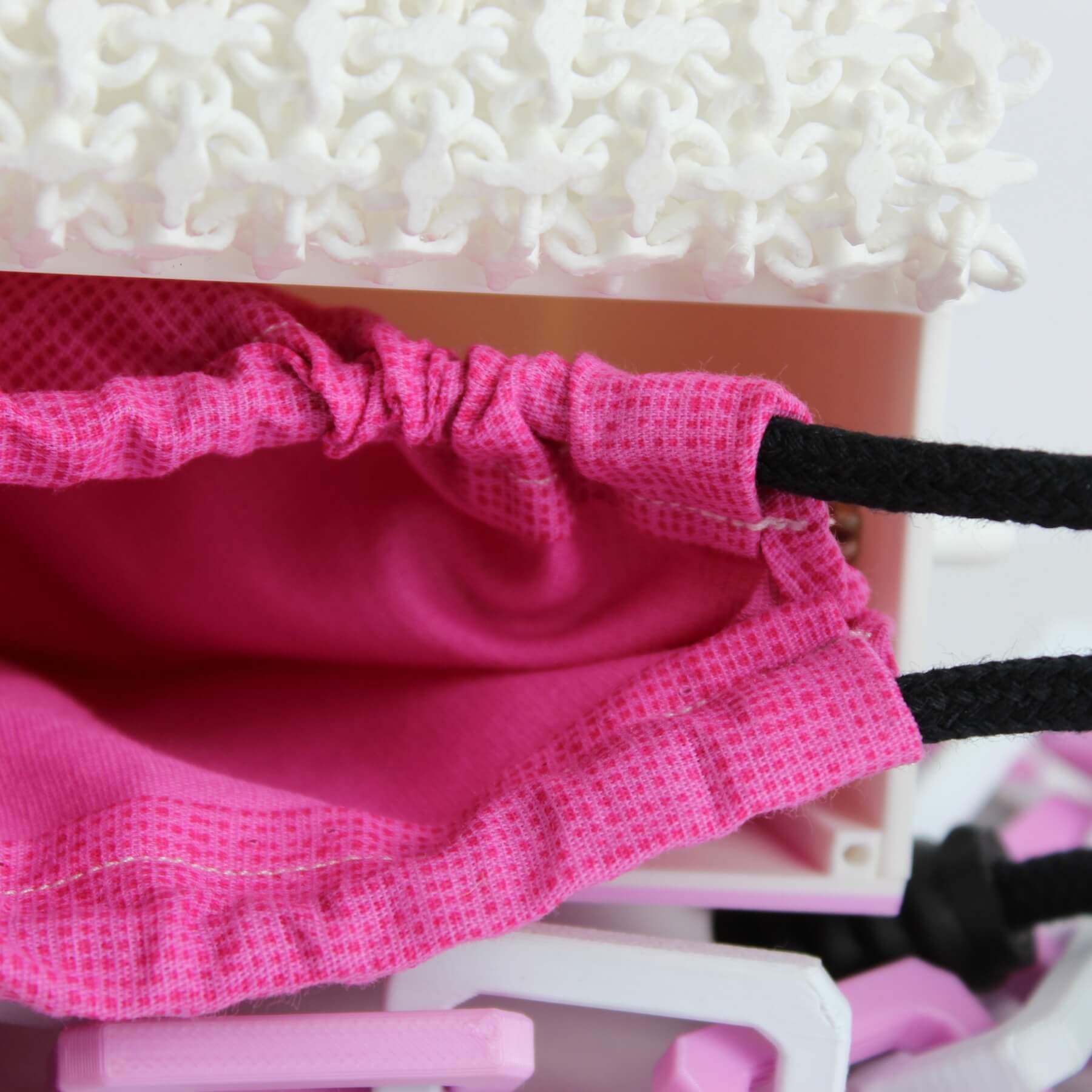 Interior da bolsa mostrando saquinho rosa com cordão preto para proteção de objetos