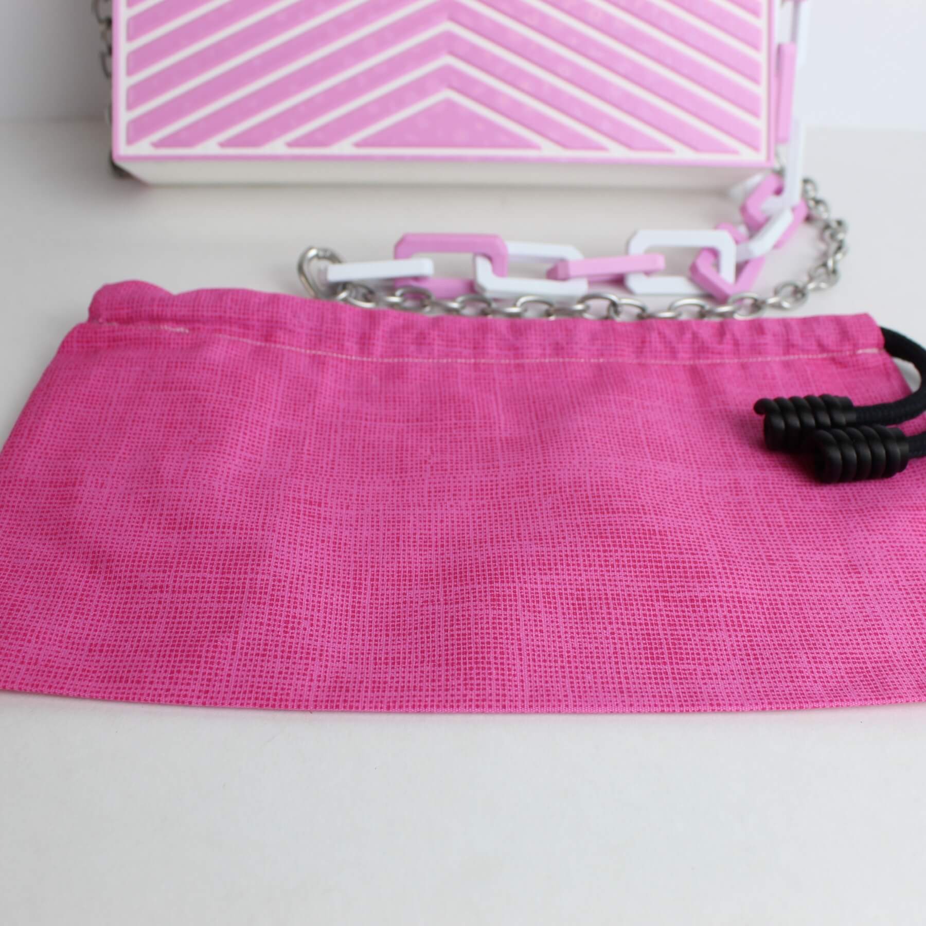 Bolsa com o saquinho rosa artesanal posicionado à frente, exibindo os acabamentos