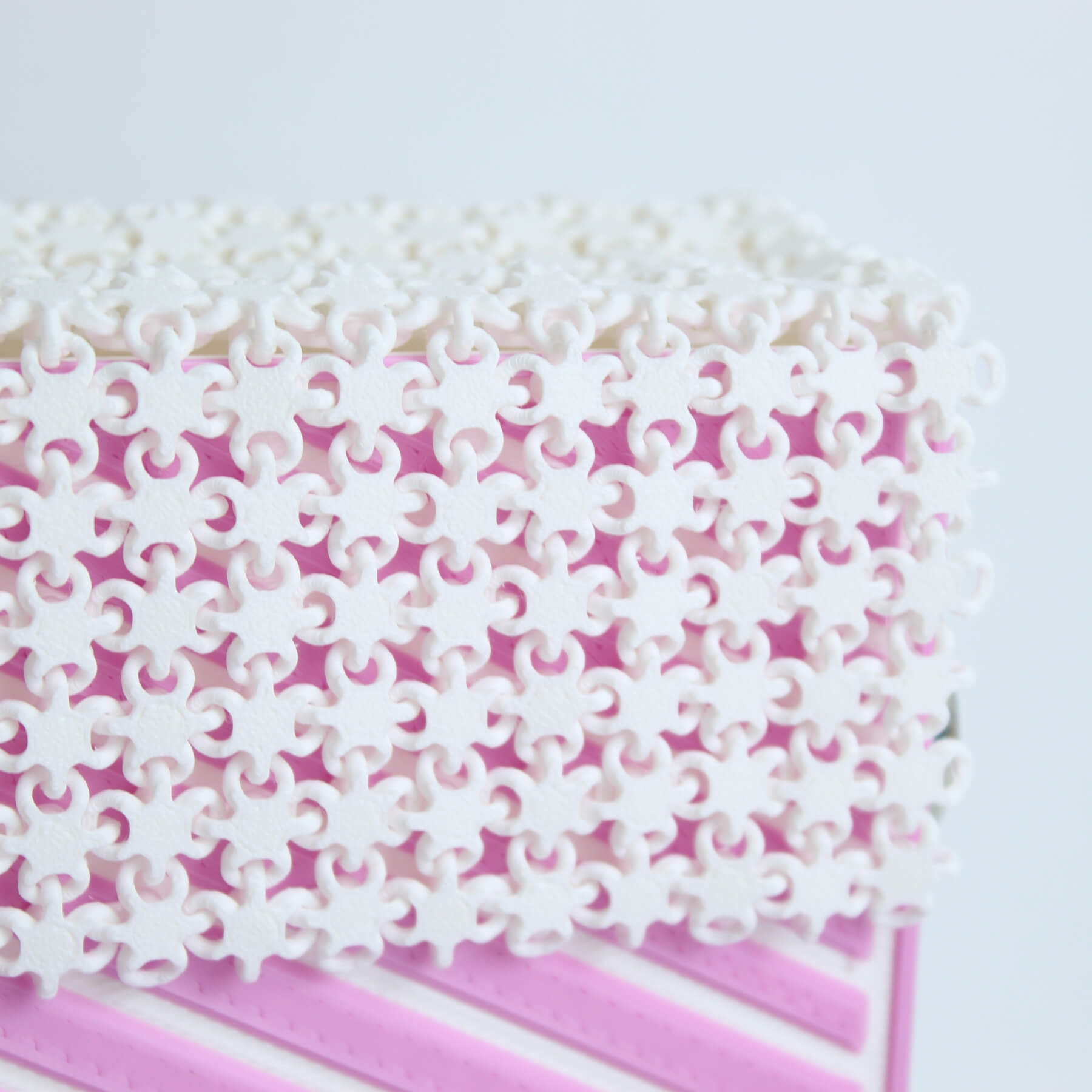 Estrutura superior da bolsa com padrão vazado artístico branco sobre fundo rosa