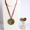 Conjunto com colar de flor verde em cordão vermelho e brincos combinando em suporte branco